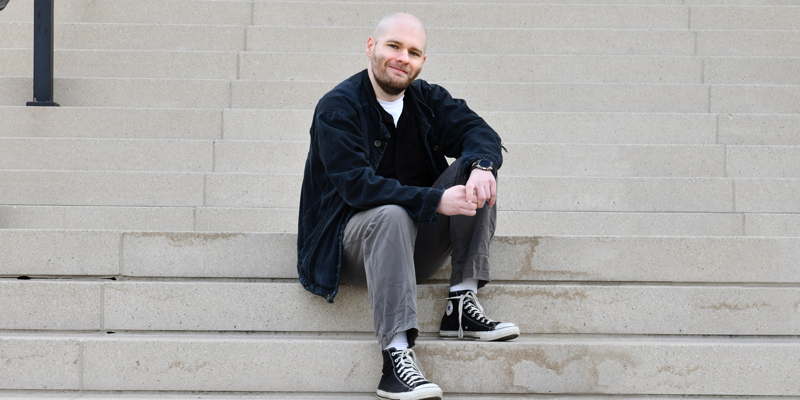 Ryan Gillispie sitting on outdoor steps looking at camera