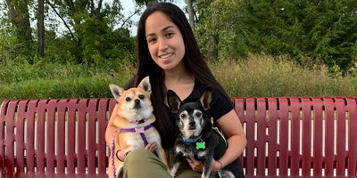 Amber Illescas sitting on a park bench holding two small dogs