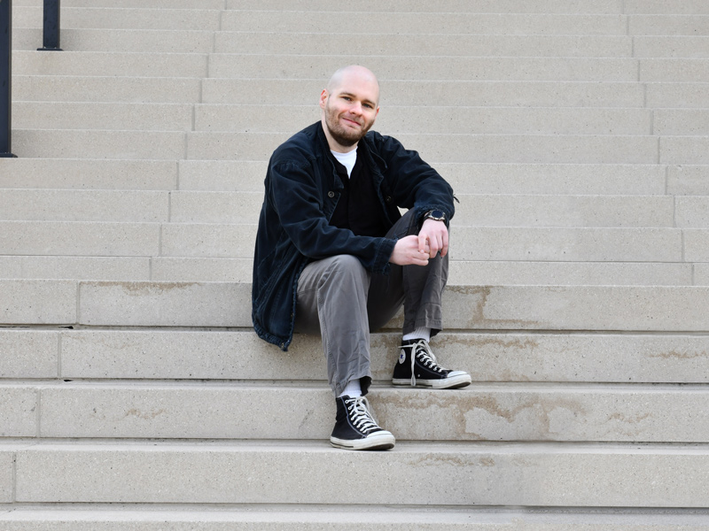 Ryan Gillispie sitting on outdoor steps looking at camera