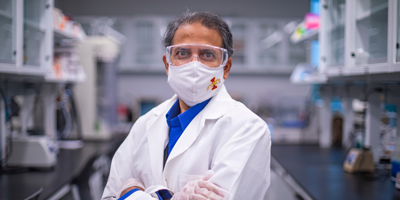 Professor Balaji Narasimhan in a lab, wearing protective goggles and lab coat