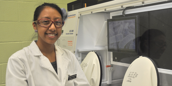 Graduate student Belen Hernandez in a laboratory wearing a lab coat