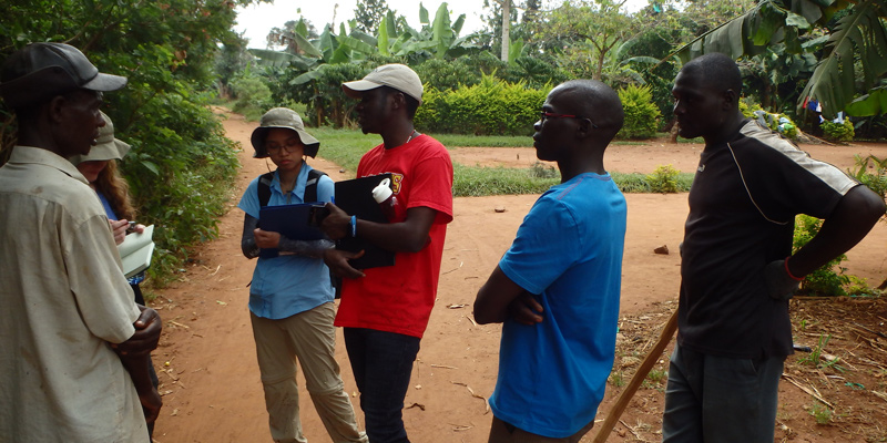 Students and farmers in rural Uganda taking notes in a field