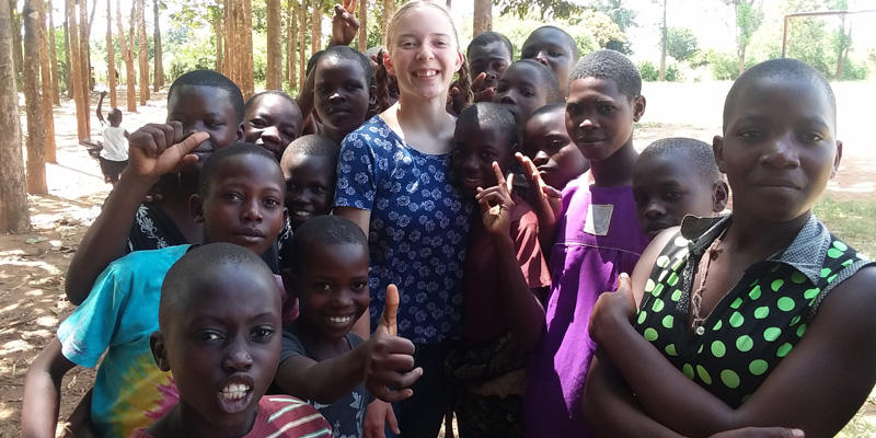 Grace Jakes poses with children and adolescents in rural Uganda