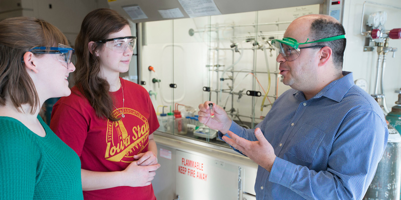 Professor and students engaged in discussion in a laboratory