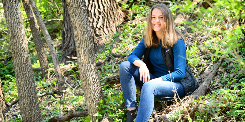 Karin Holmes sitting on a forest floor