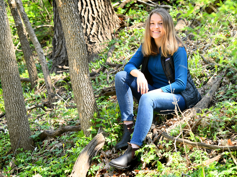Karin Holmes sitting on a forest floor